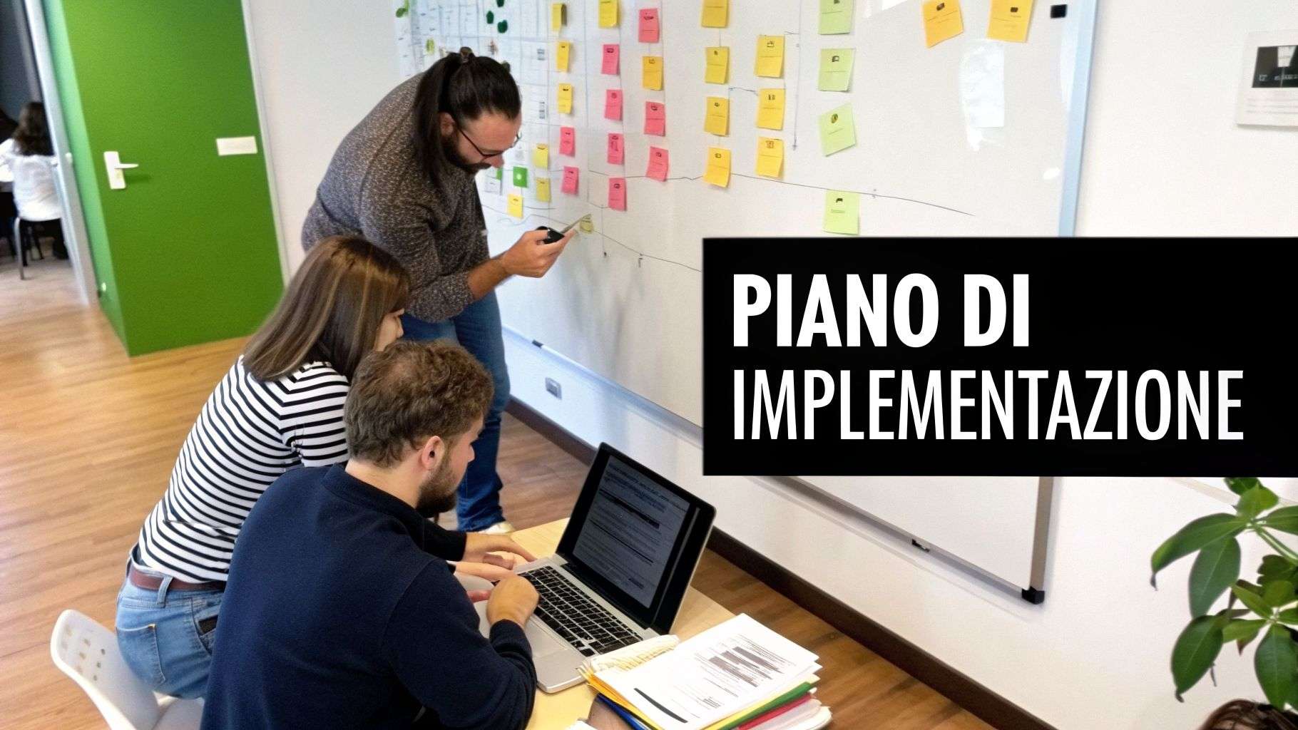 Tre persone collaborano in ufficio, esaminando un piano di implementazione su una lavagna con post-it e utilizzando un laptop.
